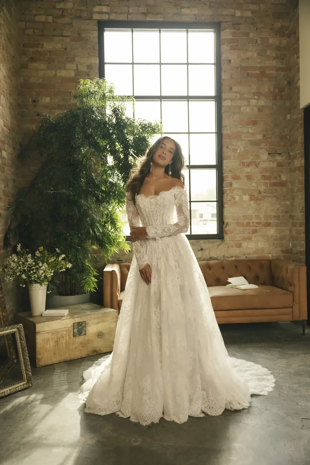 model is wearing an off the shoulder lace bridal gown